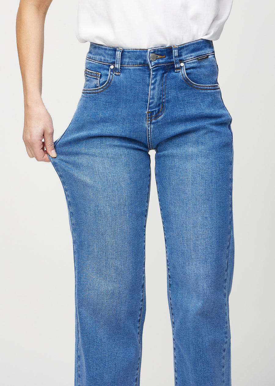 Loose-Jeans für Damen in Blau, Farbe Rivers. Ein Model dehnt den Jeansstoff am Oberschenkel, um den Stretch zu zeigen.