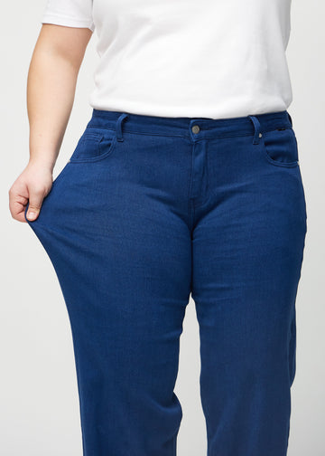 Das Plus-Size-Model zieht die Jeans am Oberschenkel auseinander, um den Stretch zu zeigen.