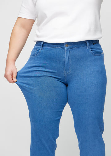 Regular-Jeans für Damen in Blau, Farbe Geraniums. Ein Plus-Size-Model dehnt den Stoff am Oberschenkel, um den Stretch zu zeigen.