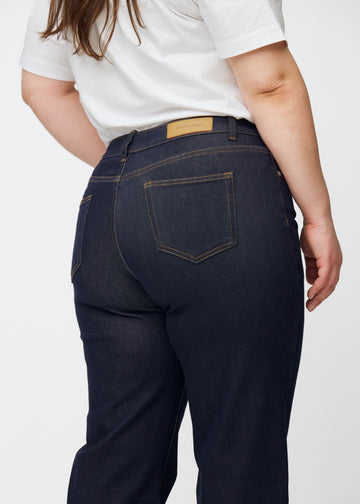 Tief dunkelblaue Denim jeans für Damen in der Farbe Midnights, von hinten in Nahaufnahme an einem Plus-Size-Model gezeigt.