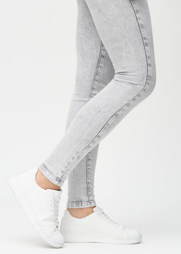 Skinny-Jeans für Damen in Hellgrau, Farbe Ashes. Nahaufnahme der eng anliegenden Beinabschlüsse am Knöchel eines Models.