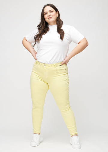 Ganzkörperbild eines Plus-Size-Models in hellgelben skinny jeans.