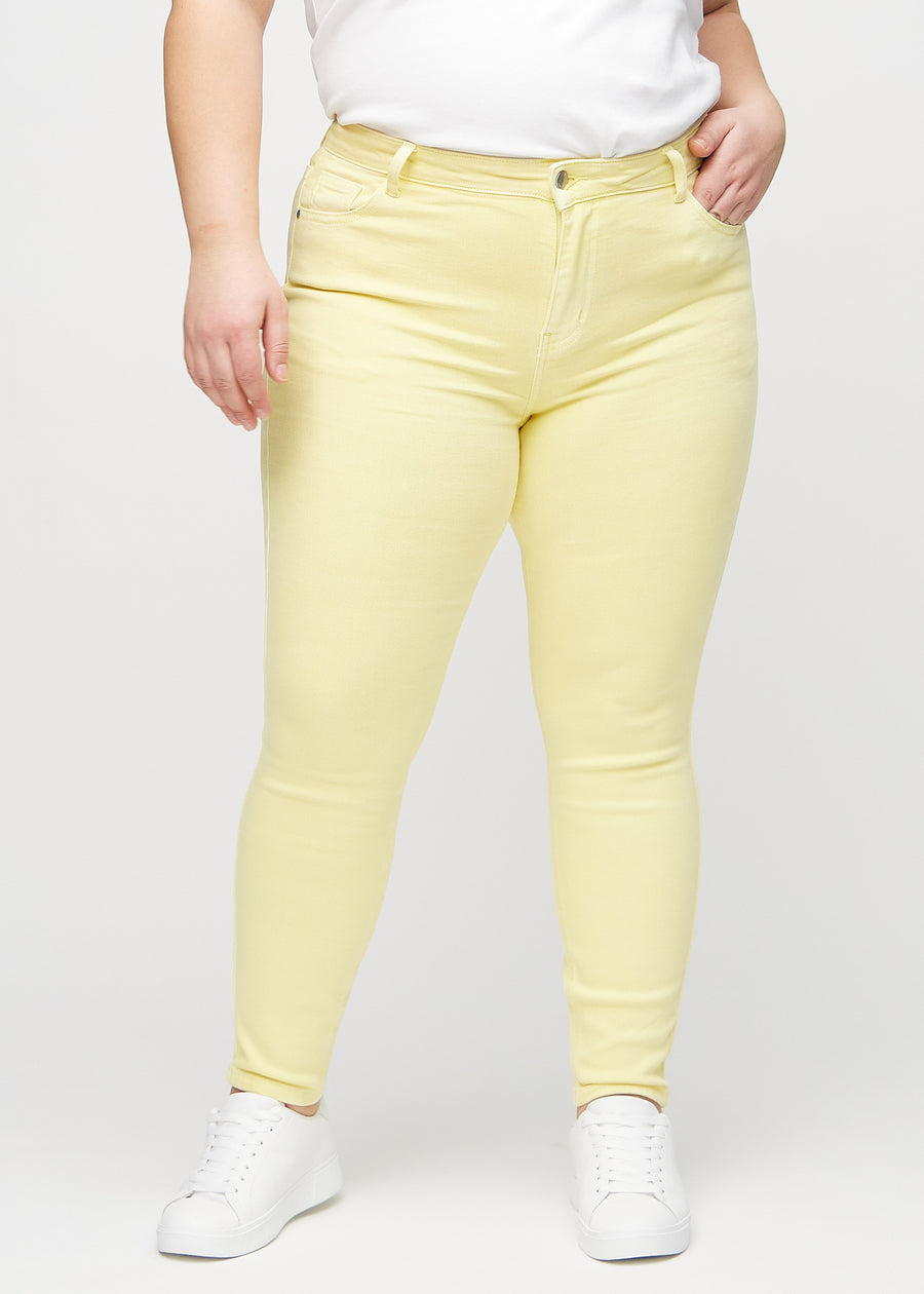 Hellgelbe skinny jeans, Modellname Lemonades, die bei einem Plus-Size-Model eng am Bein anliegen, von vorne gesehen