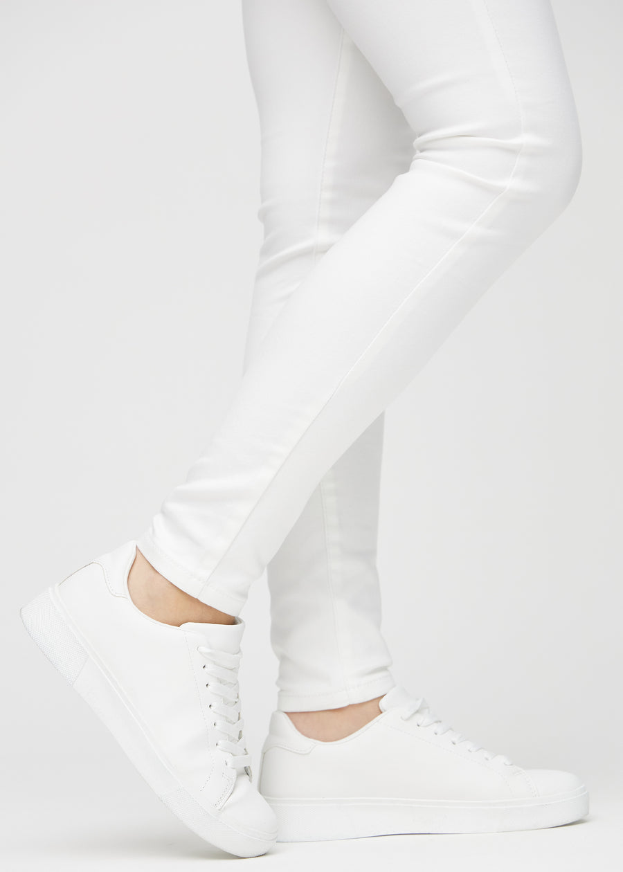 Skinny-Jeans für Damen in Weiß, Farbe Marguerites. Nahaufnahme der eng anliegenden Beinabschlüsse am Knöchel eines Models.
