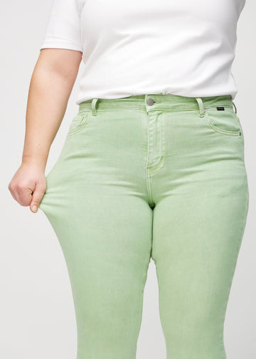 Skinny-Jeans für Damen in Hellgrün, Farbe Mints. Ein Plus-Size-Model dehnt den Jeansstoff am Oberschenkel, um den Stretch zu zeigen.