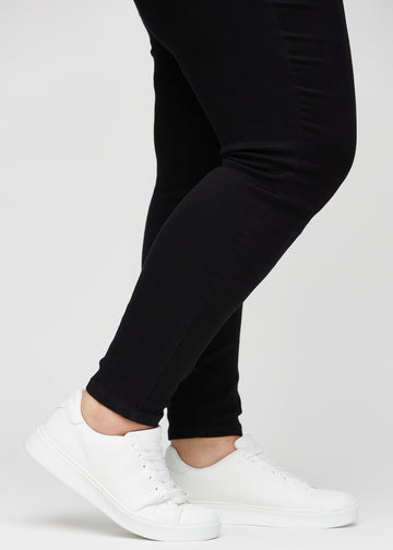 Die Knöchel eines Plus-Size-Models, sodass man sehen kann, wie eng die Jeans in einer Skinny Passform sitzen.