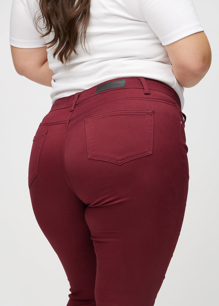 Dunkelrote skinny jeans von hinten in Nahaufnahme an einem Plus-Size-Model, um Details zu zeigen.