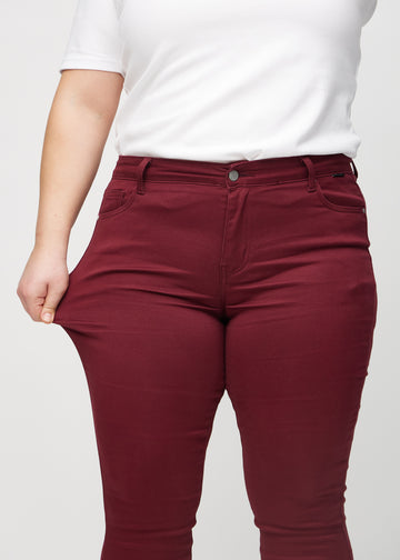 Das Plus-Size-Model zieht die Jeans am Oberschenkel auseinander, um den Stretch zu zeigen.