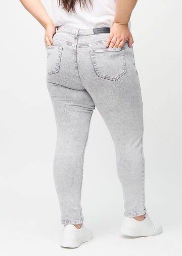 Hellgrauer Denim slim jeans von hinten an einem Plus-Size-Model gesehen, damit man das gesamte Produkt sehen kann.