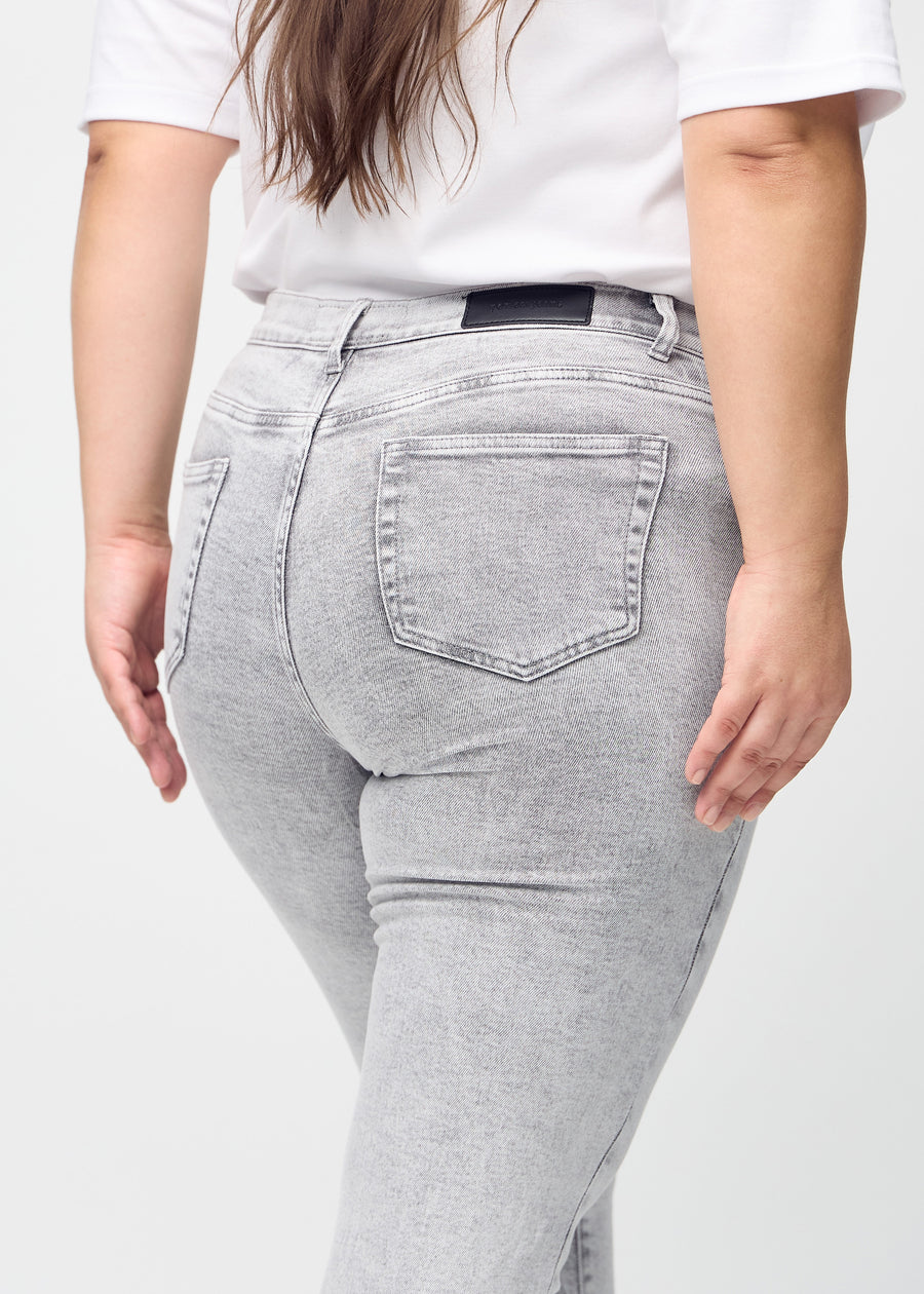 Hellgrauer Denim slim jeans von hinten in Nahaufnahme an einem Plus-Size-Model, um Details zu zeigen.