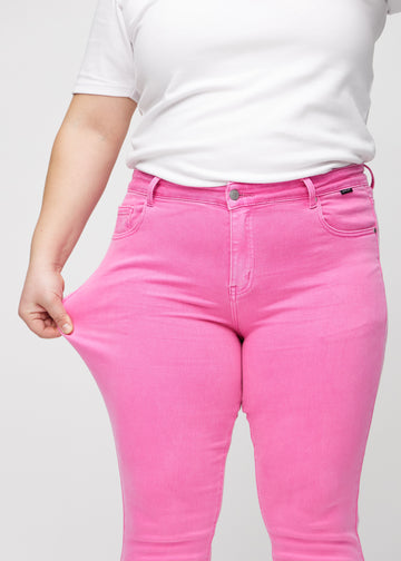 Das Plus-Size-Model zieht die Jeans am Oberschenkel auseinander, um den Stretch zu zeigen.