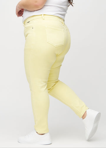 Hellgelbe slim jeans an einem Plus-Size-Model von der Seite gesehen.