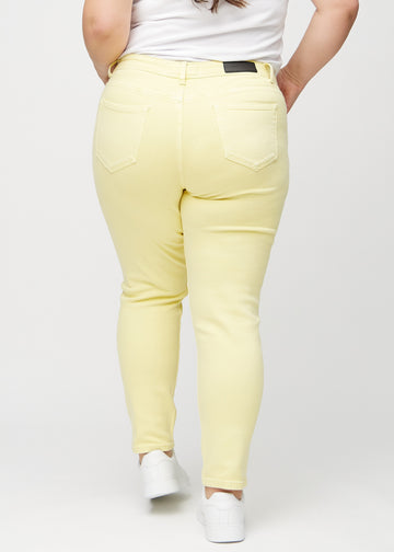 Hellgelbe slim jeans von hinten an einem Plus-Size-Model gesehen, damit man das gesamte Produkt sehen kann.
