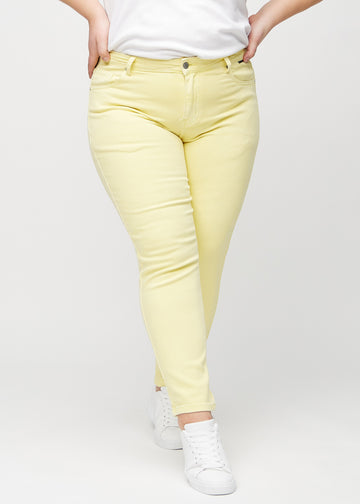 Hellgelbe slim jeans, Modellname Lemonades, die am Bein eng anliegen, jedoch am Knöchel etwas lockerer sind, an einem Plus-Size-Model von vorne gesehen.