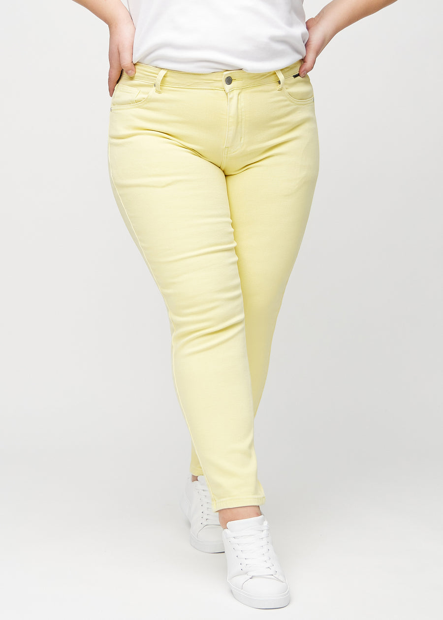 Hellgelbe slim jeans, Modellname Lemonades, die am Bein eng anliegen, jedoch am Knöchel etwas lockerer sind, an einem Plus-Size-Model von vorne gesehen.