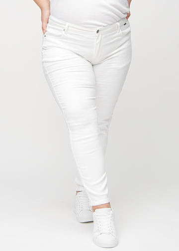Weiße slim jeans, Modellname Marguerites, die eng am Bein sitzen, aber am Knöchel etwas lockerer sind, an einem Plus-Size-Model, von vorne gesehen.