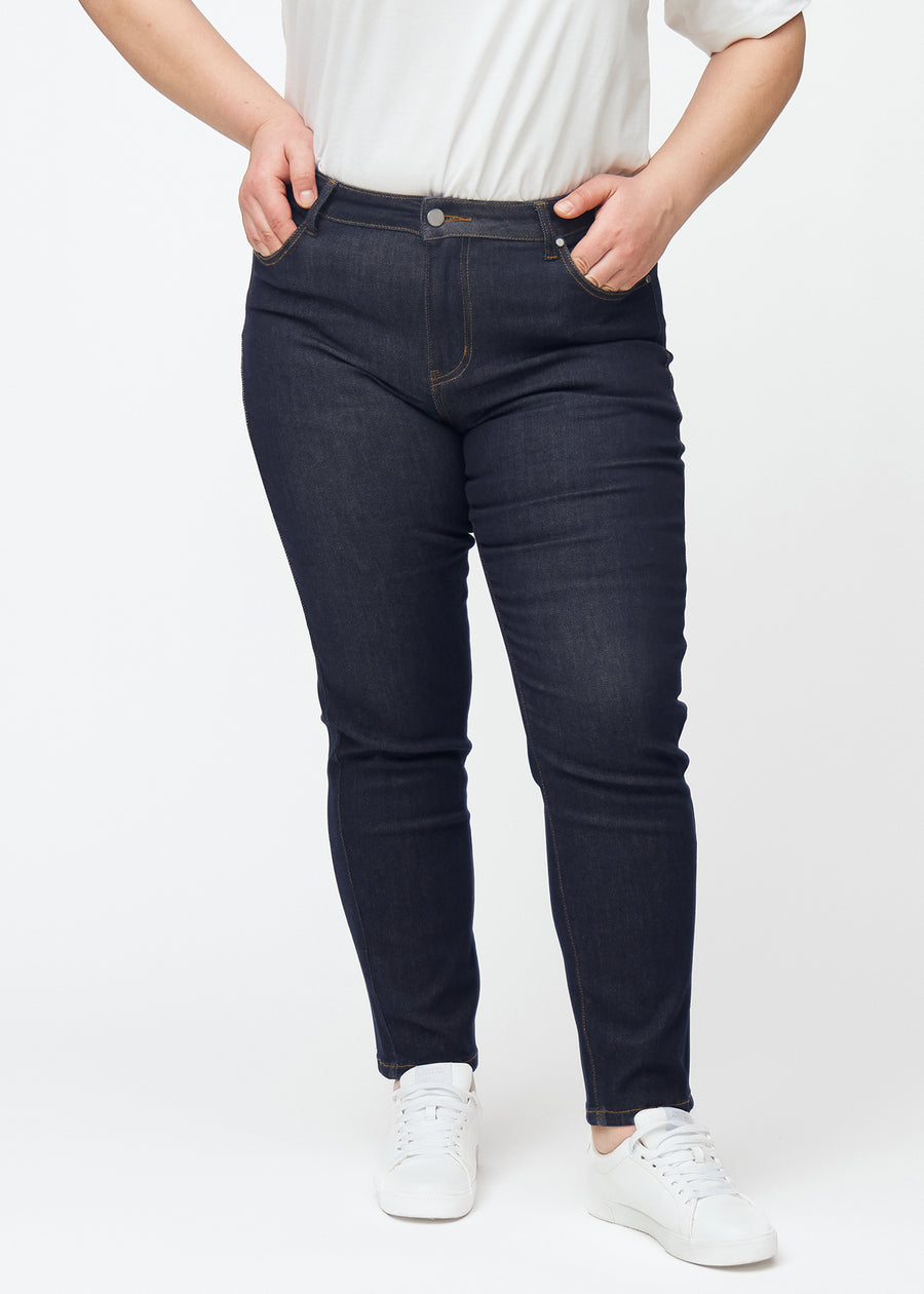 Tief dunkelblaue Denim jeans für Damen in der Farbe Midnights mit slim Passform, von vorne an einem Plus-Size-Model gesehen.