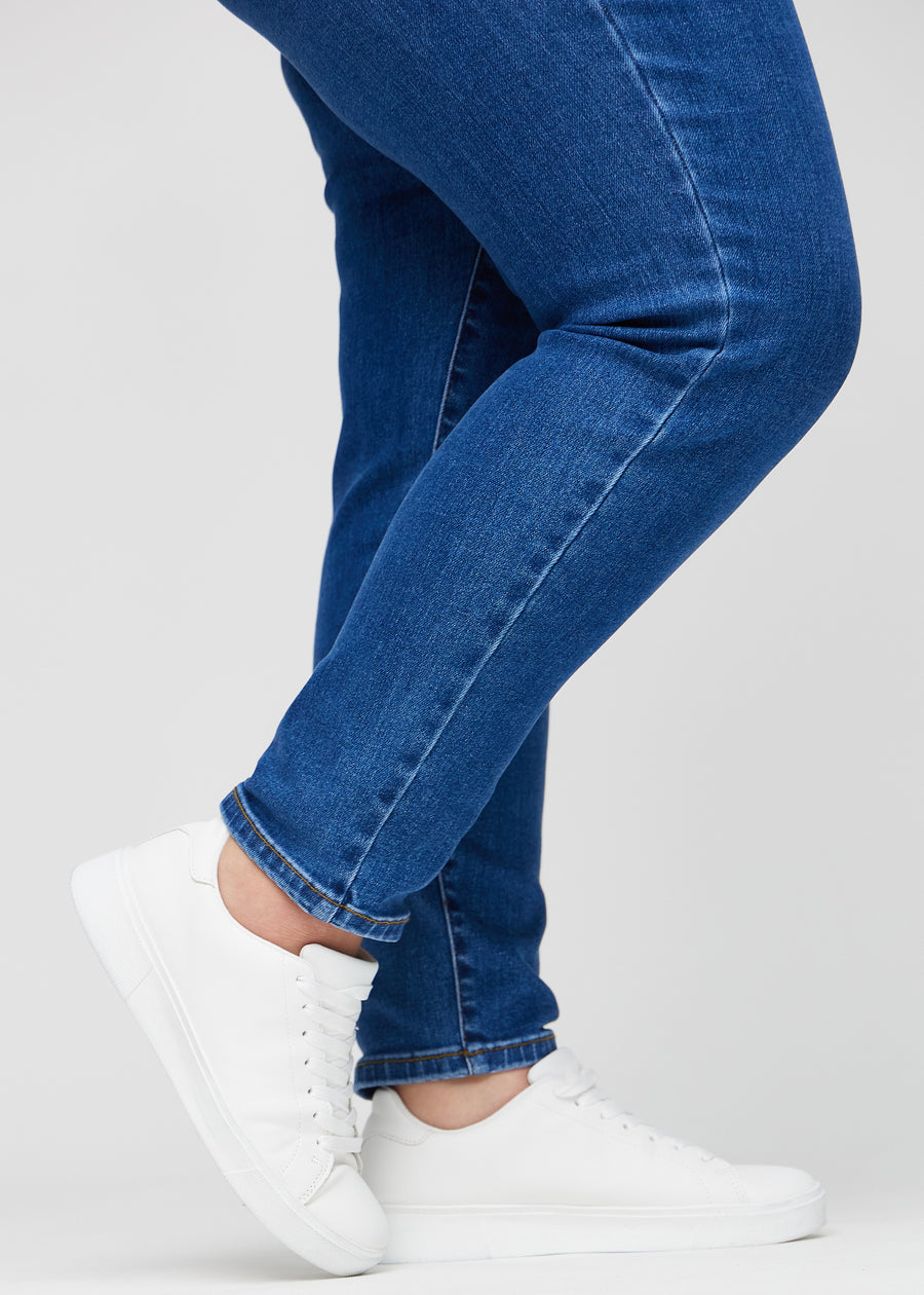 Slim-Jeans für Damen in Dunkelblau, Farbe Oceans. Nahaufnahme an den Knöcheln eines Plus-Size-Models, um die Passform am Beinabschluss zu zeigen.