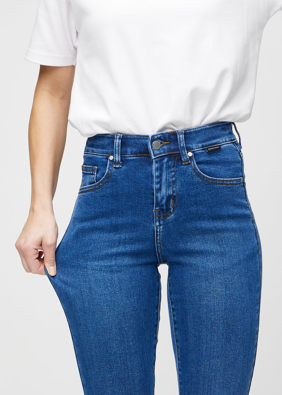 Slim-Jeans für Damen in Dunkelblau, Farbe Oceans. Ein Model zieht am Jeansstoff am Oberschenkel, um den Stretch zu zeigen.