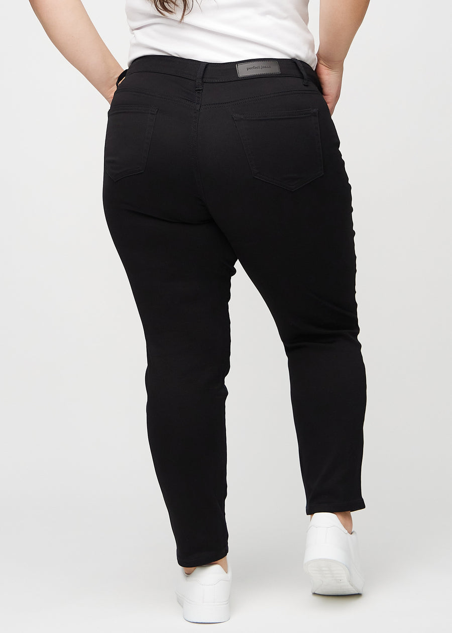 Schwarze slim jeans von hinten an einem Plus-Size-Model gesehen, sodass man das gesamte Produkt sehen kann.
