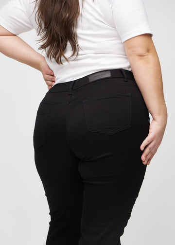 Schwarze slim jeans von hinten nah an einem Plus-Size-Model aufgenommen, um Details zu zeigen.