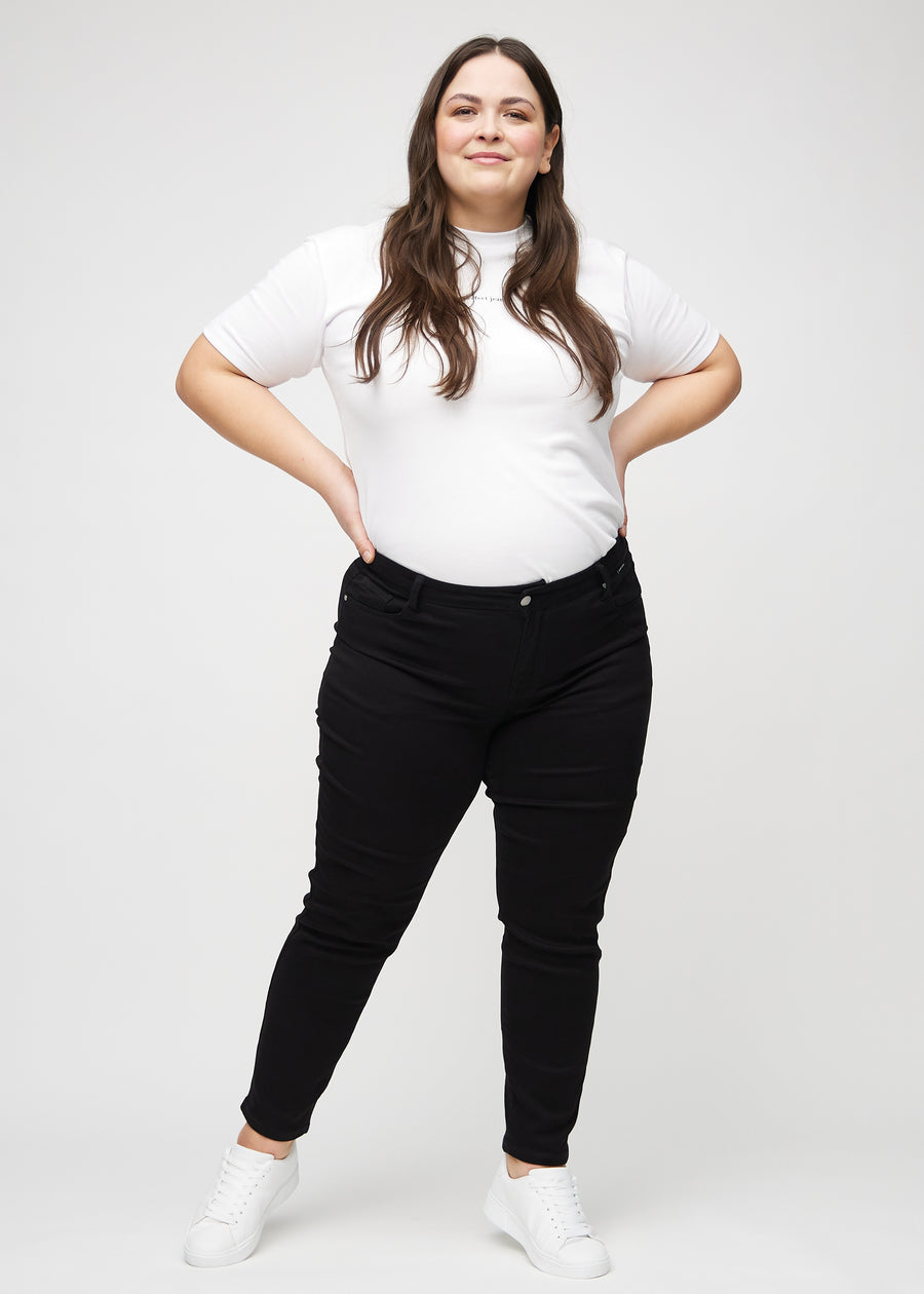 Ganzkörperbild eines Plus-Size-Models in schwarzen slim jeans.