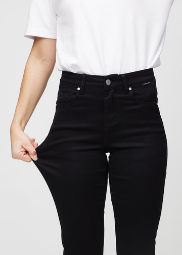 Das Model dehnt die Jeans am Oberschenkel, um den Stretch zu zeigen.