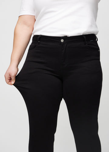 Das Plus-Size-Model dehnt die Jeans am Oberschenkel, um den Stretch zu zeigen.