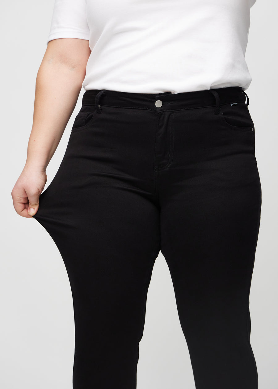 Das Plus-Size-Model dehnt die Jeans am Oberschenkel, um den Stretch zu zeigen.