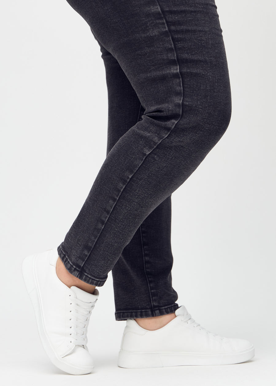 Slim-Jeans für Damen in Dunkelgrau, Farbe Shadows. Nahaufnahme an den Knöcheln eines Plus-Size-Models, um die Passform am Beinabschluss zu zeigen.
