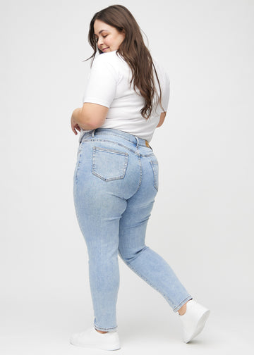 Heller Denim slim jeans von der Seite an einem Plus-Size-Model gesehen.