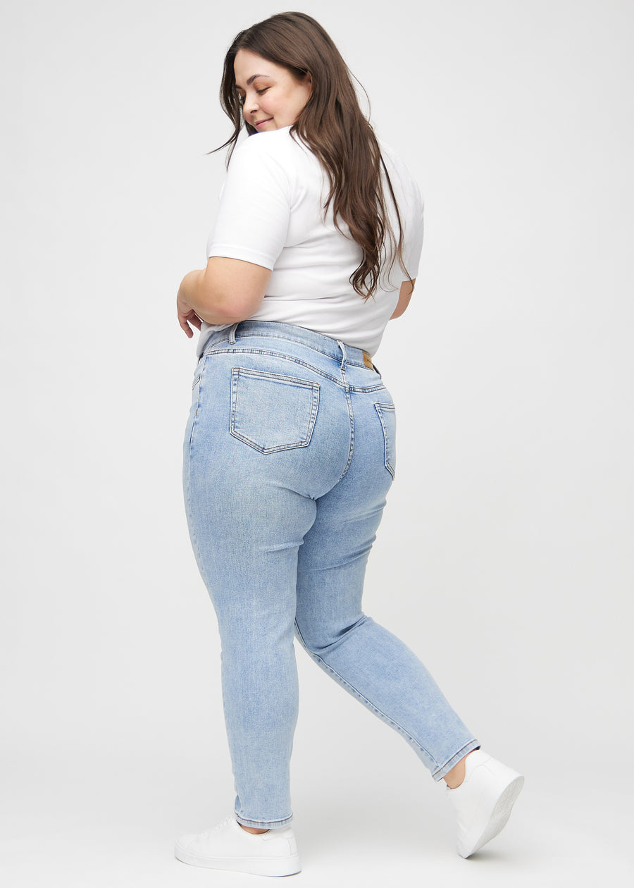 Heller Denim slim jeans von der Seite an einem Plus-Size-Model gesehen.