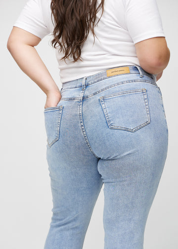 Heller Denim slim jeans von hinten in Nahaufnahme an einem Plus-Size-Model, um Details zu zeigen.