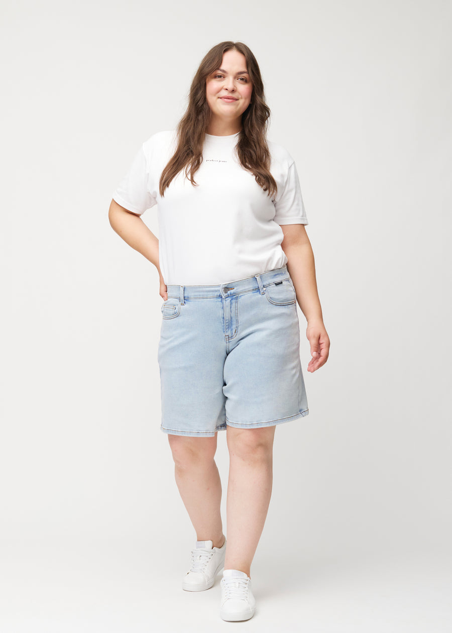 Ganzkörperaufnahme eines weiblichen Models in hellblauen Waves Denim-Shorts mit mittelhohem Bund (Mid Rise) und Loose Fit.
