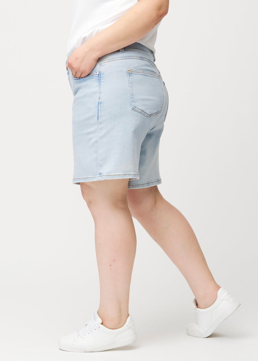 Seitenansicht eines weiblichen Models in hellblauen Waves Denim-Shorts mit mittelhohem Bund (Mid Rise) und Loose Fit.