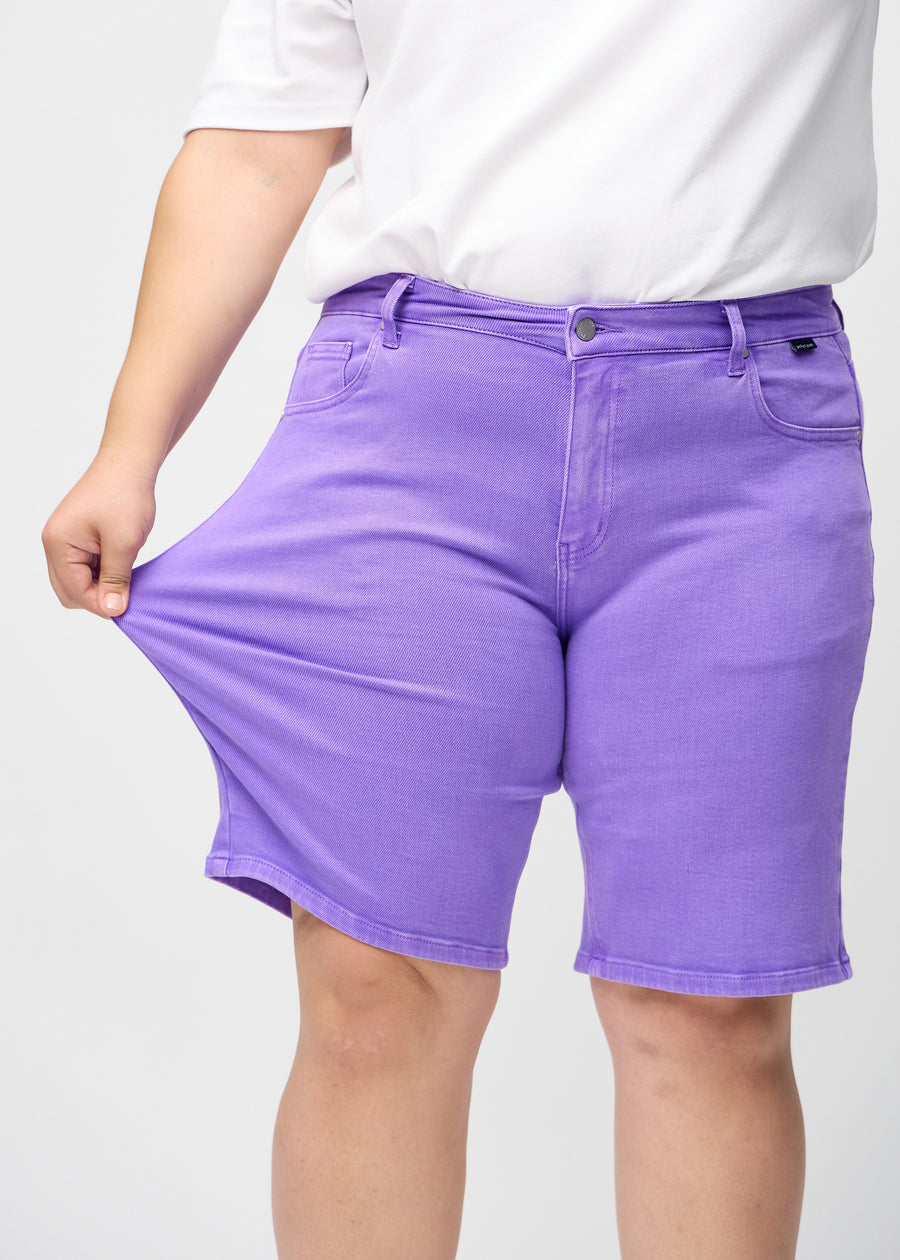 Das Plus-Size-Model zieht die Shorts am Oberschenkel, um den Stretch zu zeigen.