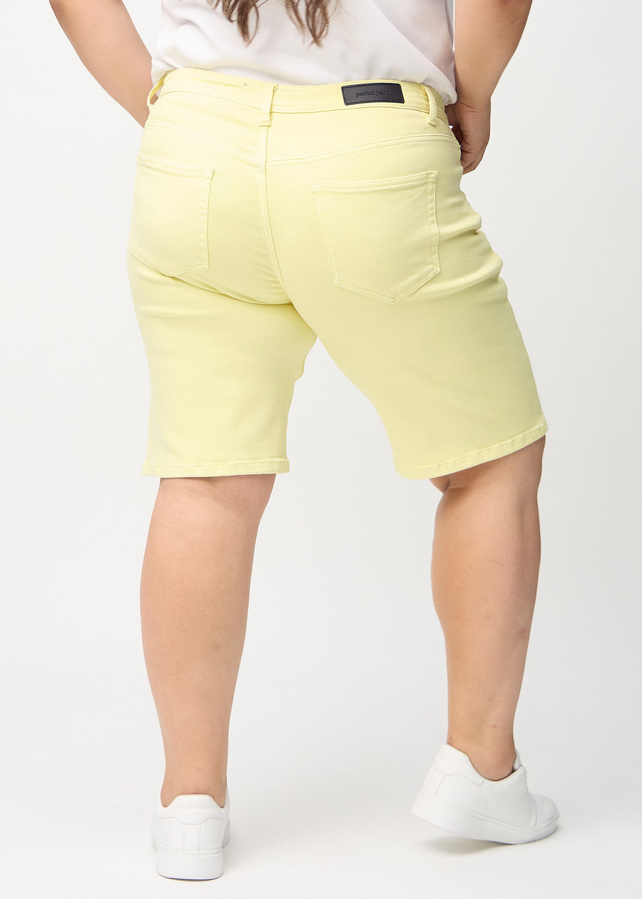 Hellgelbe regular Middle Shorts von hinten an einem Plus-Size-Model gesehen, sodass man das ganze Produkt sehen kann.