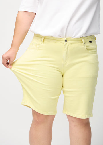 Das Plus-Size-Model zieht die Shorts am Oberschenkel auseinander, um den Stretch zu zeigen.