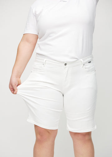 Das Plus-Size-Model zieht die Shorts am Oberschenkel auseinander, um den Stretch zu zeigen.