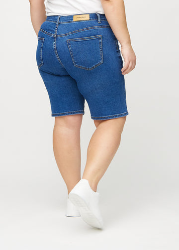 Dunkle Denim-regular middle shorts von hinten an einem Plus-Size-Model gesehen, sodass man das gesamte Produkt sehen kann.