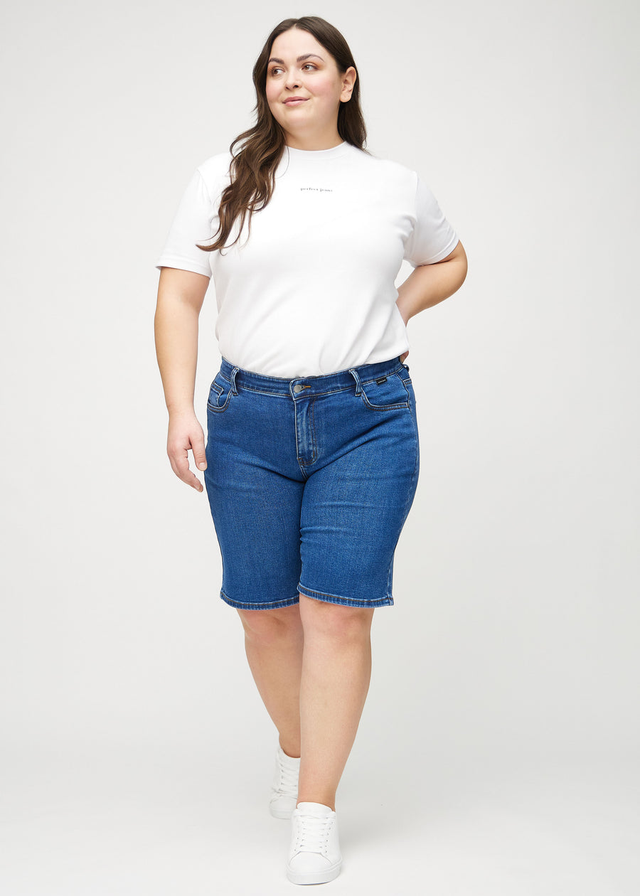 Ganzkörperbild eines Plus-Size-Models in dunklen Denim-regular middle shorts.