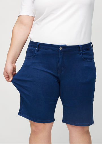 Das Plus-Size-Model zieht die Shorts am Oberschenkel auseinander, um den Stretch zu zeigen.