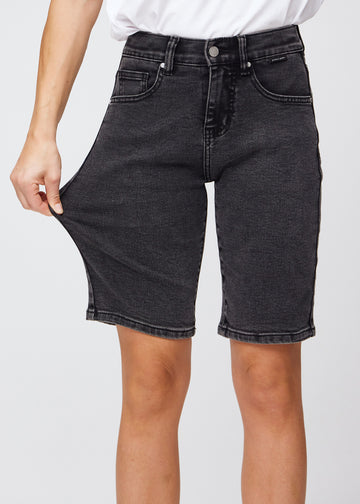 Frau, die ein Paar knielange dunkelgraue Denim-Shorts dehnt