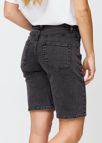 Frau in knielangen dunkelgrauen Denim-Shorts von hinten gesehen, sodass man die Denim-Details sehen kann