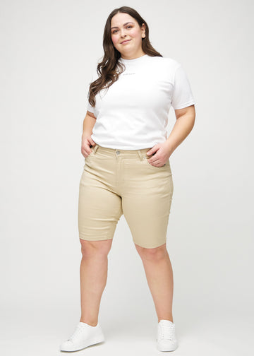 Ganzkörperbild eines Plus-Size-Models in beige skinny middle shorts.
