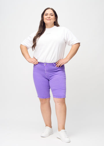 Ganzkörperbild eines Plus-Size-Models in lila skinny middle shorts.