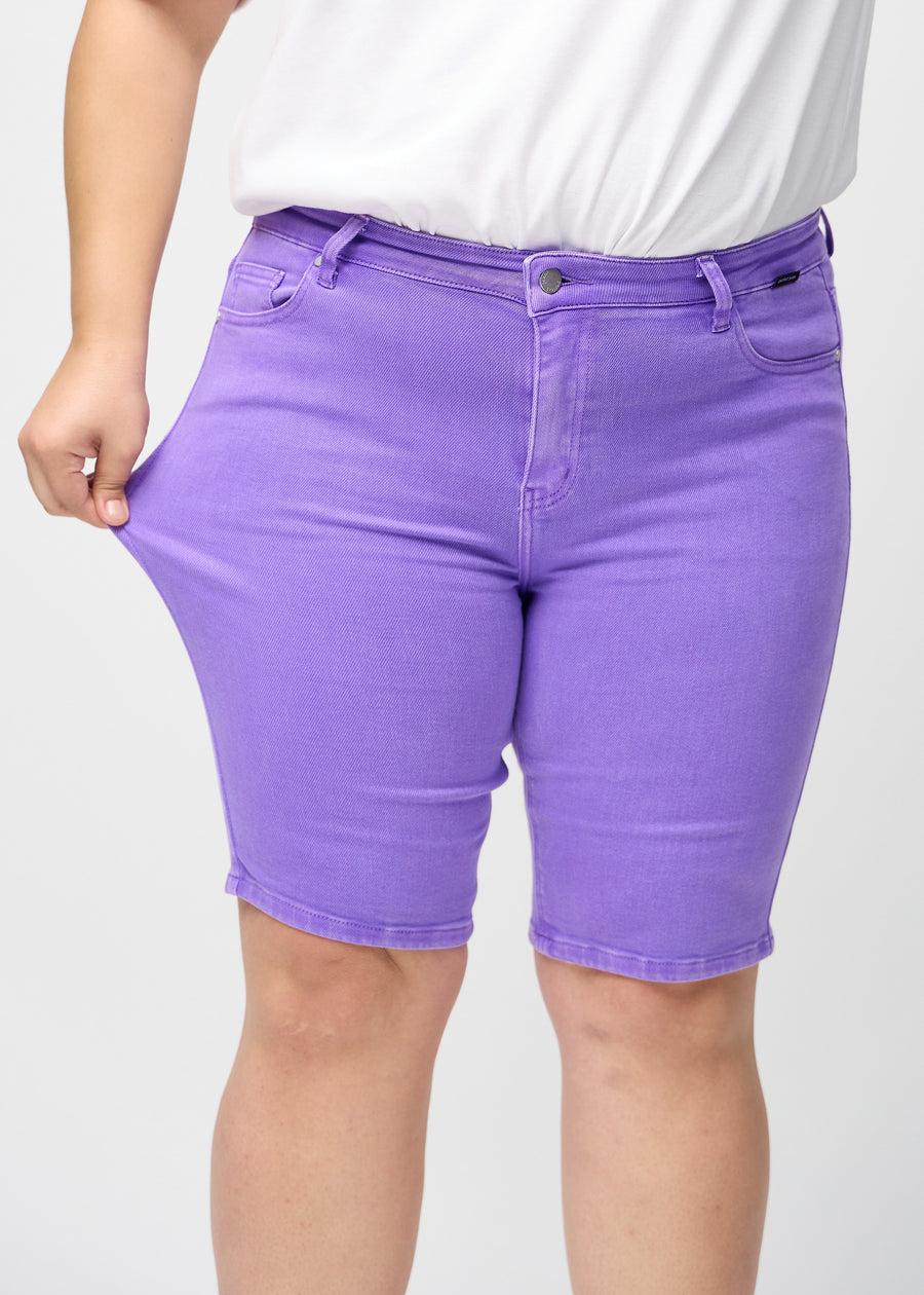Das Plus-Size-Model zieht die Shorts am Oberschenkel auseinander, um den Stretch zu zeigen.