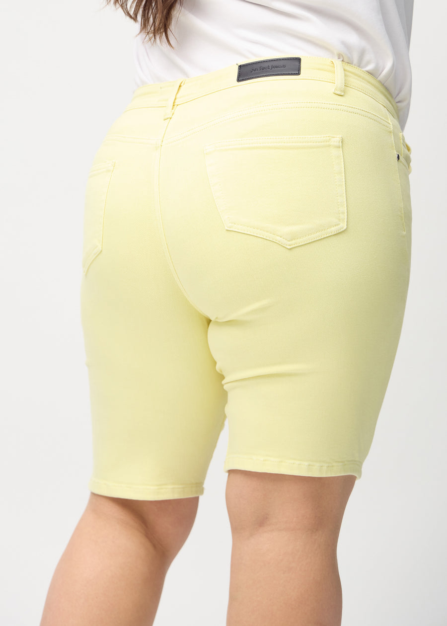 Hellgelbe skinny middle shorts von hinten in Nahaufnahme an einem Plus-Size-Model, um Details zu zeigen.