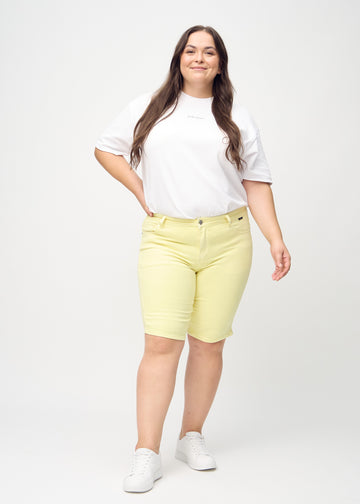 Ganzkörperbild eines Plus-Size-Models in hellgelben skinny middle shorts.