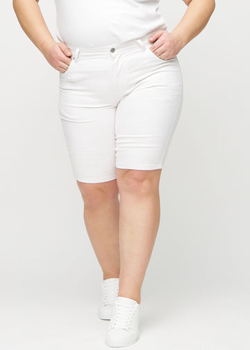Weiße skinny Middle Shorts, Modellname Marguerites, die eng am Oberschenkel anliegen und knapp über dem Knie enden, an einem Plus-Size-Model von vorne gesehen.